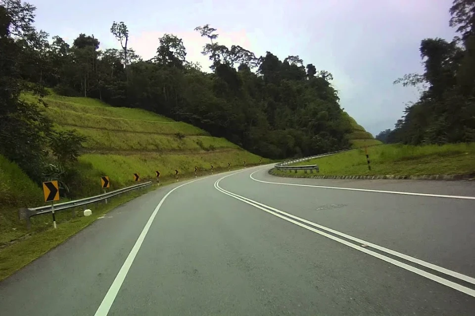 A winding mountain road leading to Cameron Highlands, Malaysia, surrounded by lush greenery.