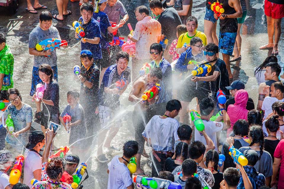 People celebrating Songkran Festival in Thailand with water splashing on the streets