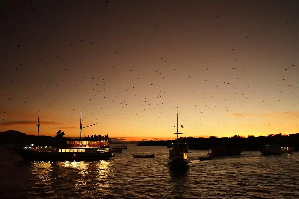 Golden sunset over the calm sea and islands in Komodo National Park, viewed from a boat