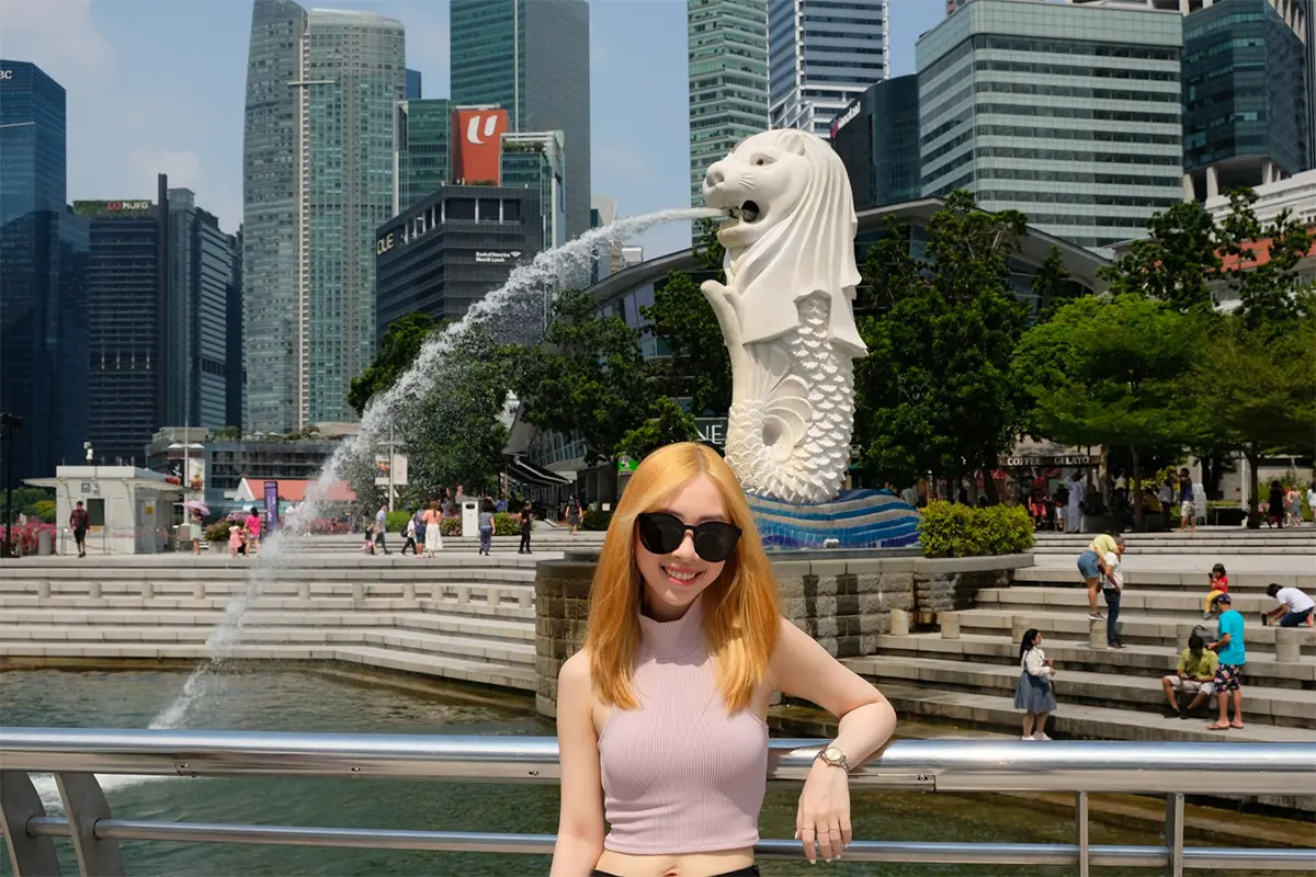 Visitors posing with the original Merlion at Merlion Park, emphasizing its iconic status.