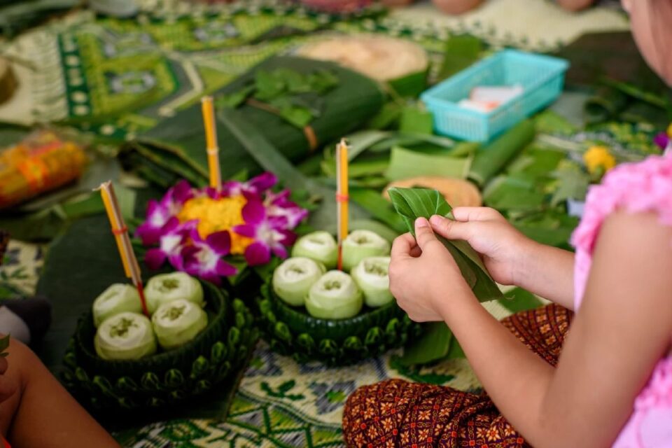 Thai locals making traditional krathongs from banana leaves and flowers before the festival.