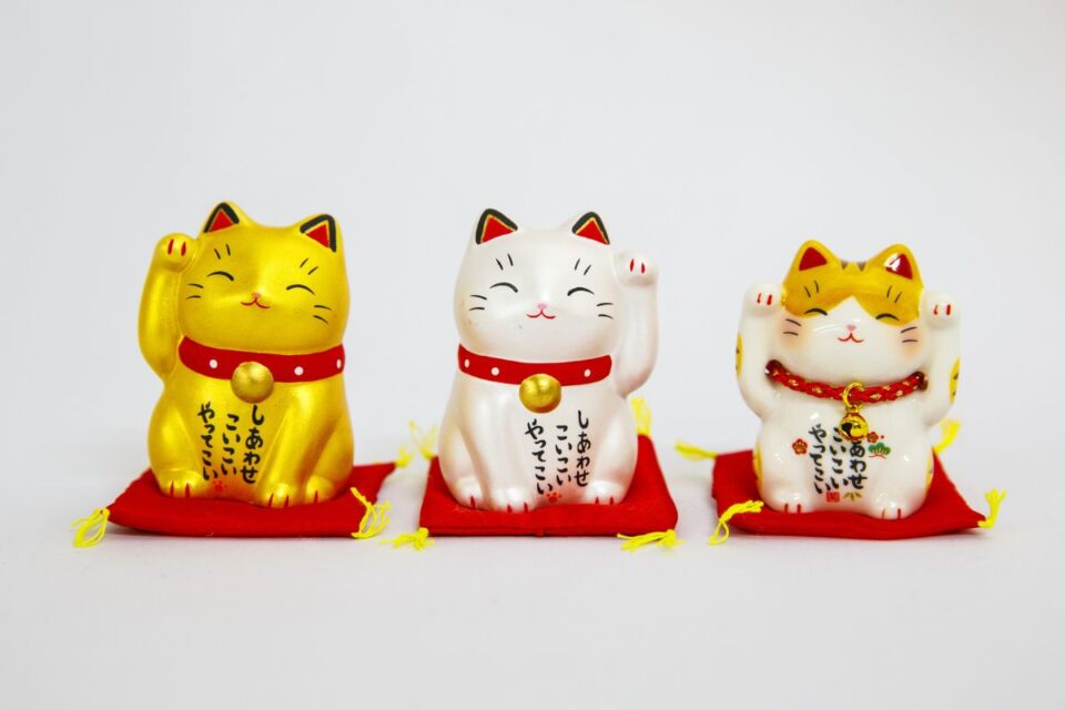 Lucky Maneki Neko figurines with raised paws on red cushions